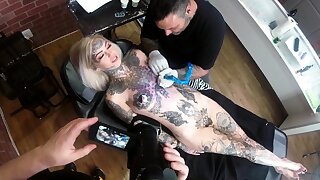 Sascha plays give Amber Luke while she gets tattooed